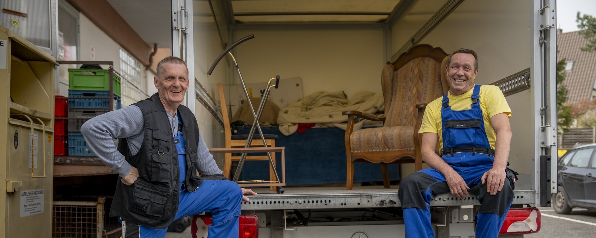 Zwei Maenner mit Arbeitskleidung stehen vor einem LKW 