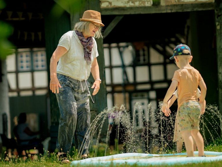 Eine Frau spielt mit zwei Kindern in einem Planschbecken.