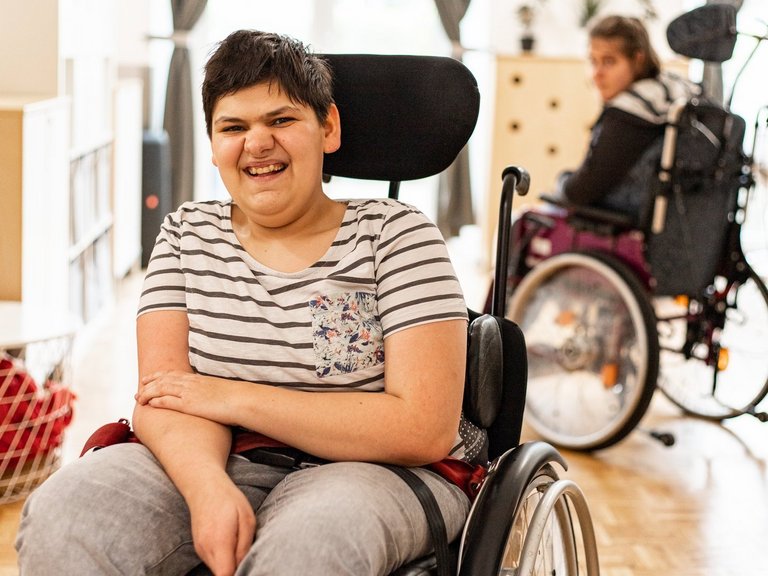 Bewohnerin im Rollstuhl und lächelt glücklich