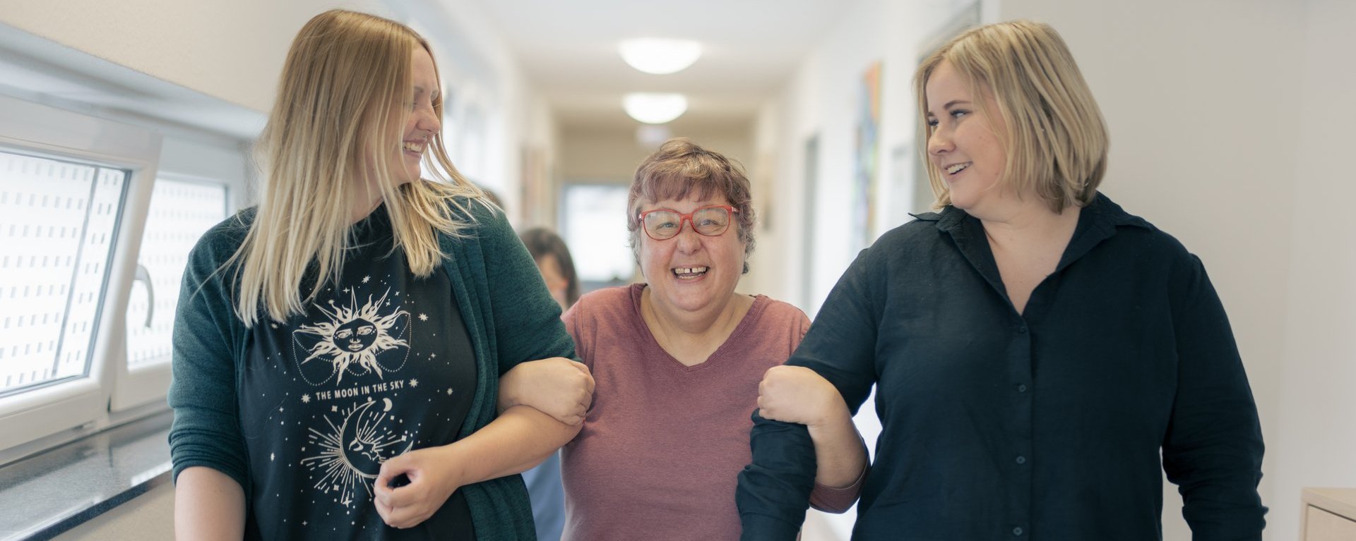 drei Frauen gehen nebeneinander und klinken sich Arm in Arm ein 